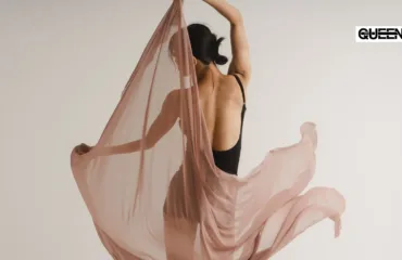 Dancewear for Women How to Choose Clothes for Studio Training Woman in a black backless outfit dances with flowing dusty-pink fabric against a neutral backdrop; QUEEN logo in the top-right corner.