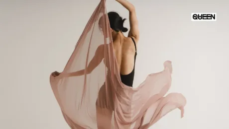 Dancewear for Women How to Choose Clothes for Studio Training Woman in a black backless outfit dances with flowing dusty-pink fabric against a neutral backdrop; QUEEN logo in the top-right corner.