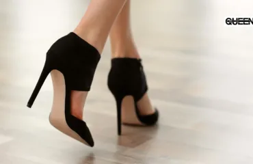 Pole Dance Heels for Beginners How to Choose Your First Pair Close-up of black high-heeled sandals stepping on a light wood floor, with a QUEEN logo in the top-right corner.