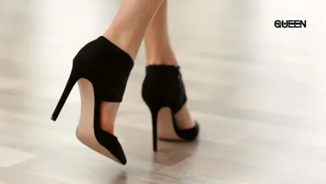 Pole Dance Heels for Beginners How to Choose Your First Pair Close-up of black high-heeled sandals stepping on a light wood floor, with a QUEEN logo in the top-right corner.