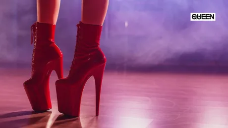 Pleaser Heels The Complete Guide for Pole Dance Close-up of red high-heeled platform boots on a wooden stage with purple haze and a QUEEN logo in the top-right.