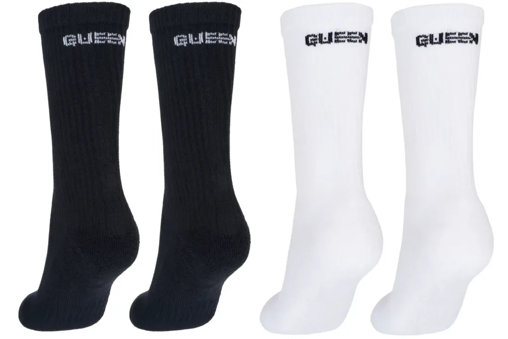 image Four socks arranged in two black socks on the left and two white socks on the right, with GUESS branding on the cuffs.